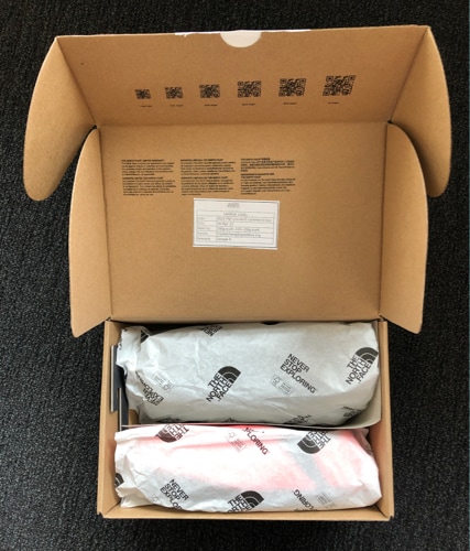 Shoes from The North Face are displayed in their box. They are packaged in paper instead of polybags.