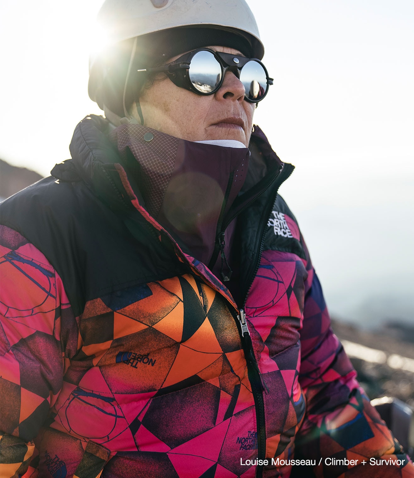 Breast cancer survivor and climber Louise Mousseau poses on a mountain wearing the Pink Ribbon Nuptse from The North Face.
