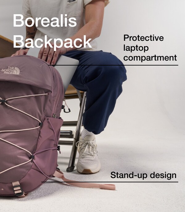 A person at a desk pulls a laptop from a dusty heather colored Borealis backpack. 