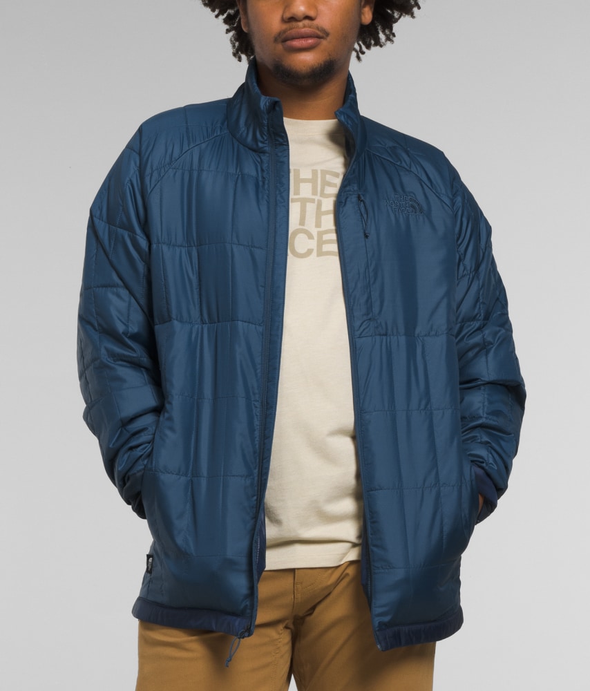 A man models a blue Circaloft Jacket with his hands in the pockets. 