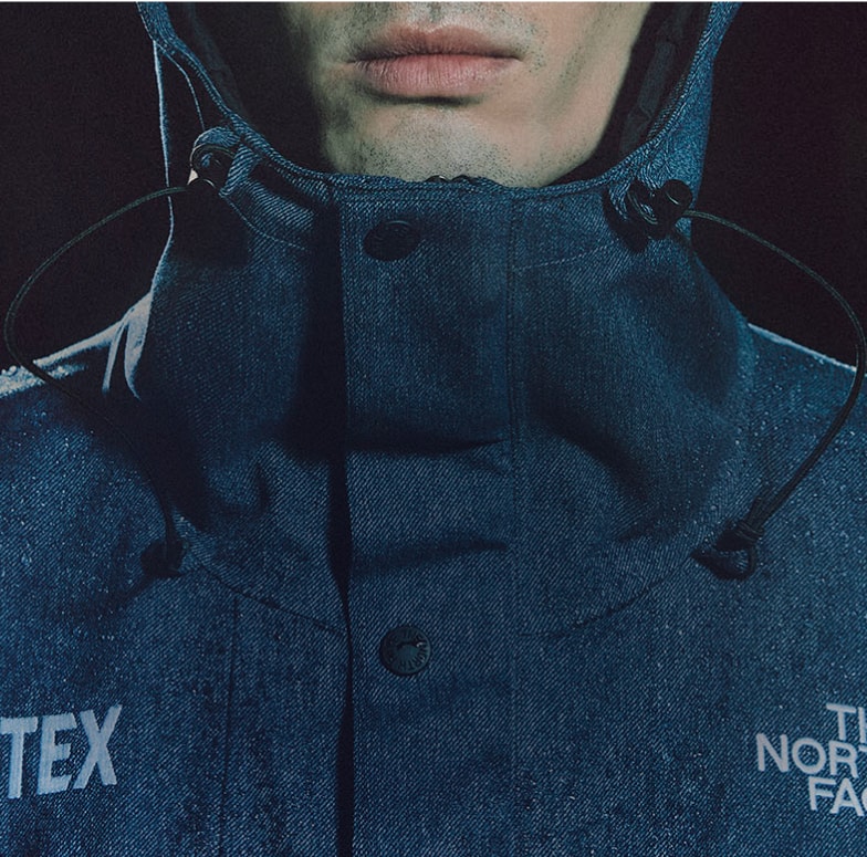 Person wearing the GTX Mountain Jacket with hood in front of a black background.
