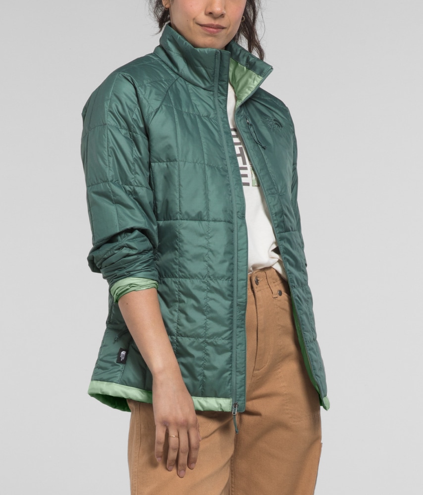 A woman models a sage-colored Circaloft Jacket with the sleeve rolled up. 