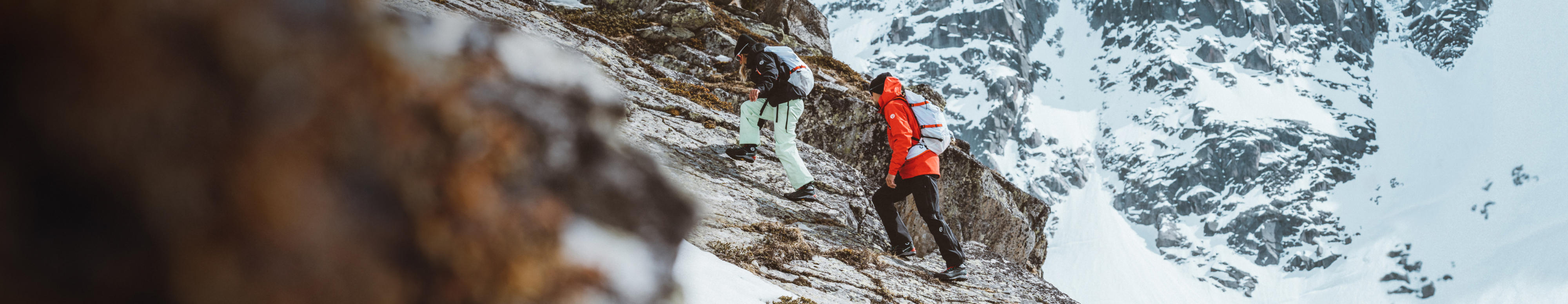 Deux personnes portant des vêtements de la série Summit de The North Face escaladent une montagne dans la neige.