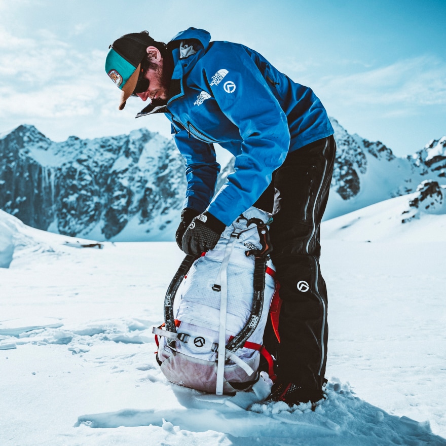 An athlete loads his backpack in a snowy landscape.