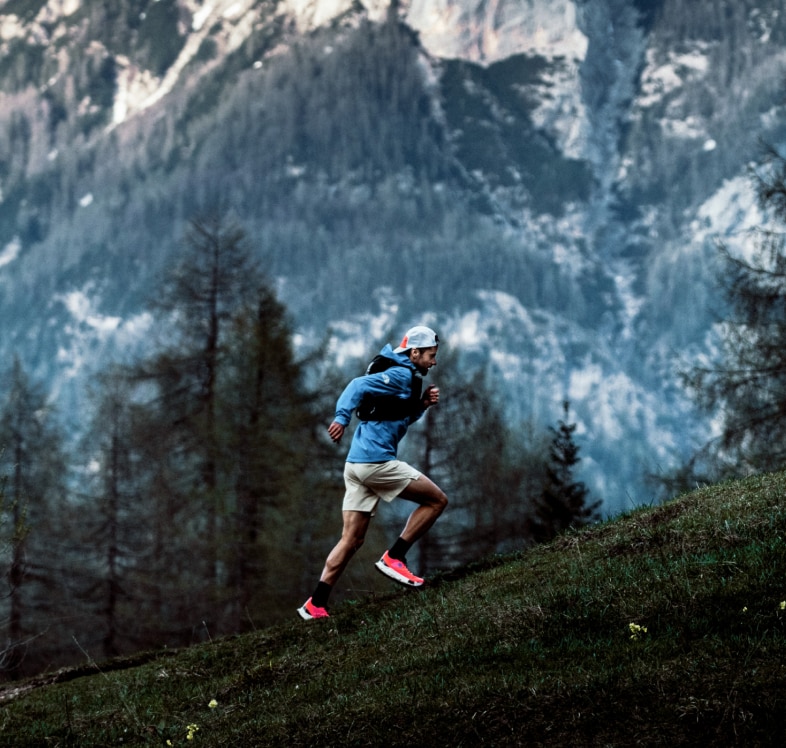 A man trail runs at dusk in Summit Series gear from The North Face.