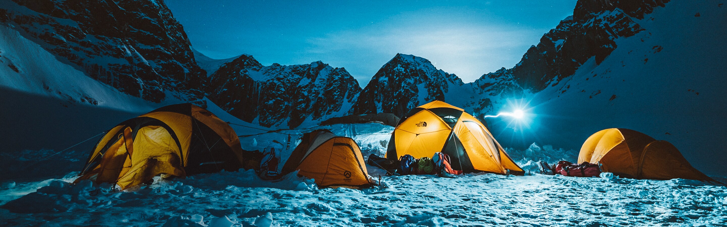 Tents from The North Face against a snowy, mountainous night sky.