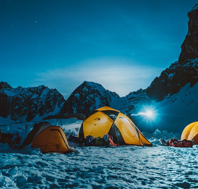 Tents from The North Face against a snowy, mountainous night sky.