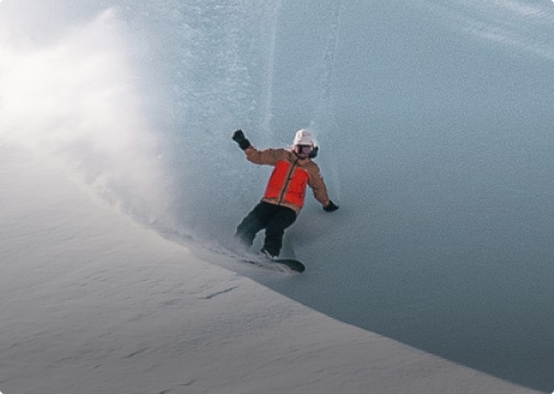 An athlete leaves a spray of snow as they carve a new line in the snow.