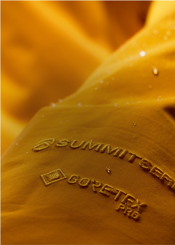 Gros plan sur le logo Summit SeriesMC et le logo GORE-TEX Pro sur le tissu GORE-TEX jaune.