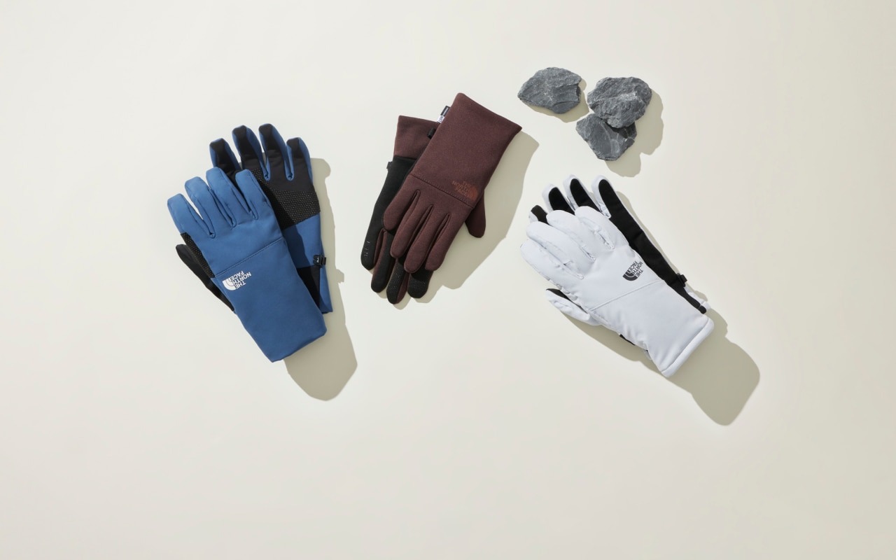 An overhead view of three pairs of gloves in multiple colors laid out on a white background. 