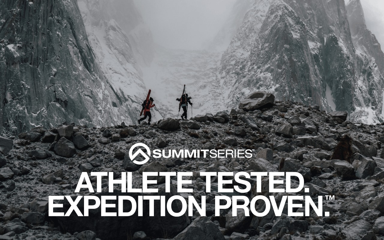 Deux athlètes The North Face, équipés d’articles de ski de haute montagne, traversent des terrains montagneux rocailleux en arborant des manteaux Summit SeriesMC.