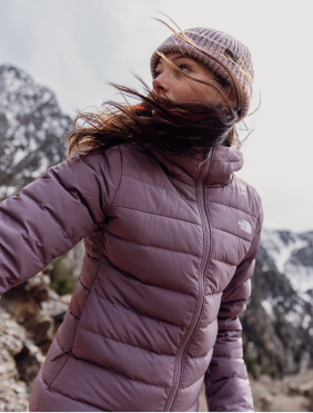 A woman wearing the Aconcagua 3 Hoodie from The North Face is standing in a snowy mountainous landscape.