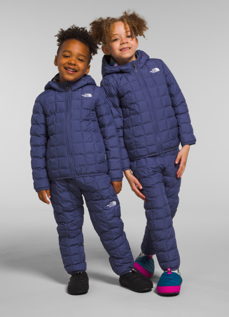 Two children wearing head-to-toe The North Face puffer jackets.