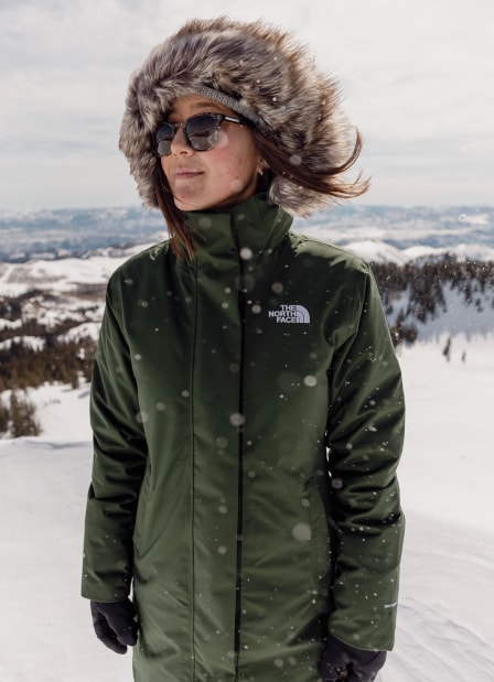 A woman wearing the Aconcagua 3 Hoodie from The North Face is standing in a snowy mountainous landscape.