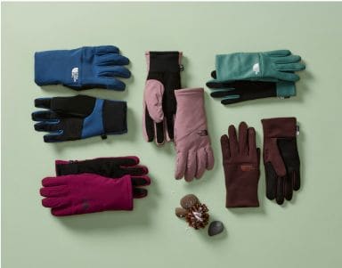A collection of The North Face gloves in front of a green background.