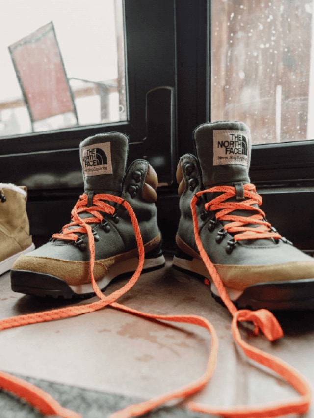 Inside a cabin, by the door, sit two different pairs of winter boots from The North Face.