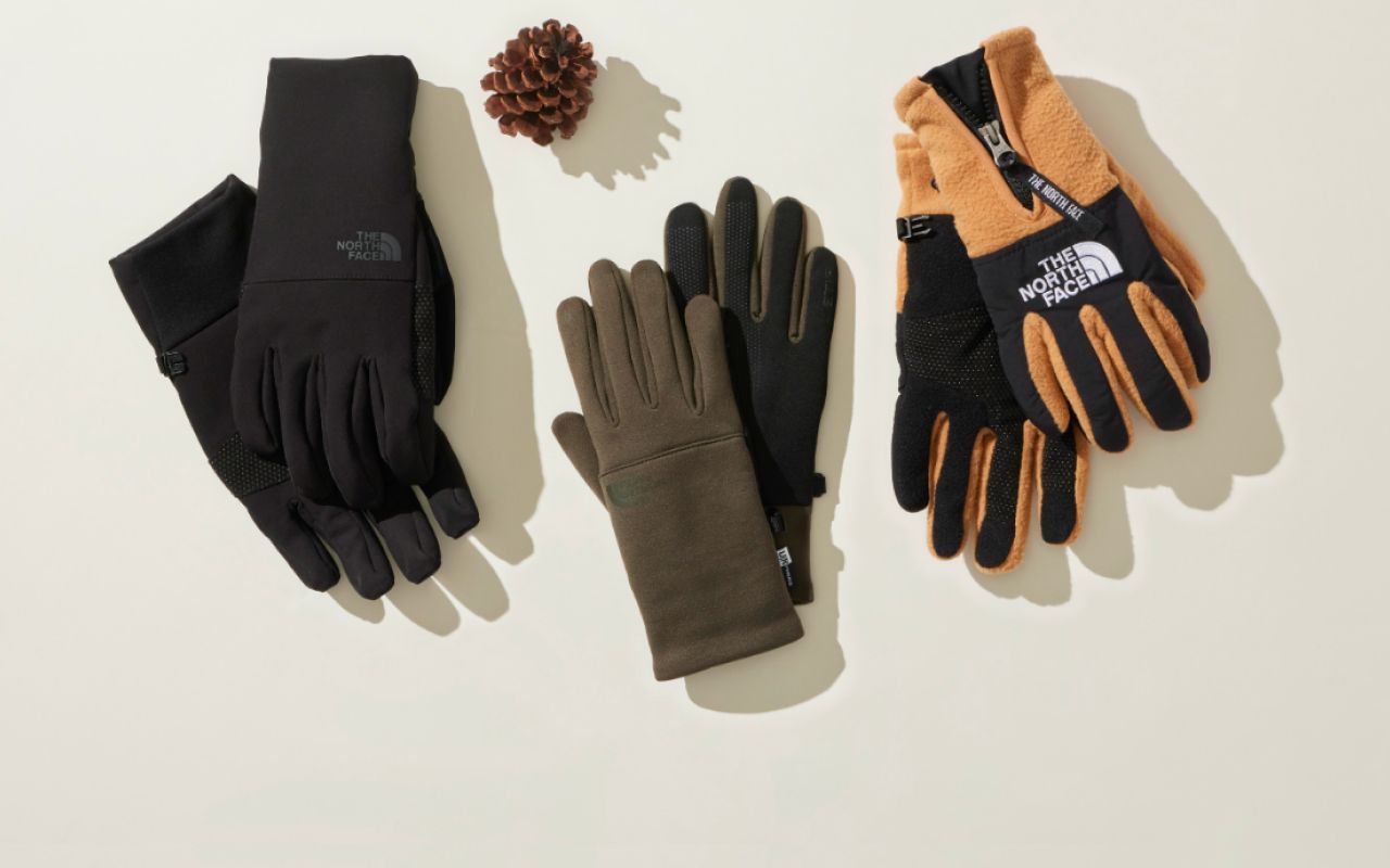 Studio laydown of three pairs of gloves from The North Face in various colors. 