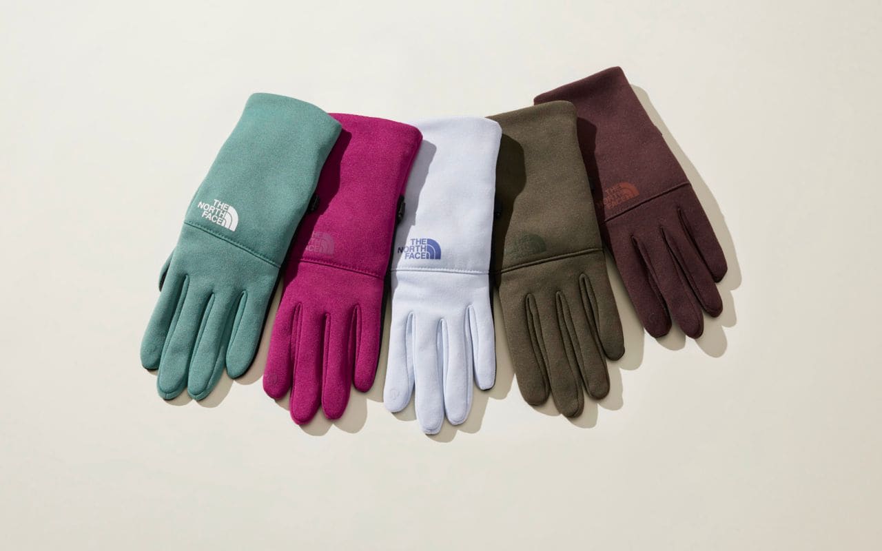 Studio laydown of five gloves from The North Face in various colors.