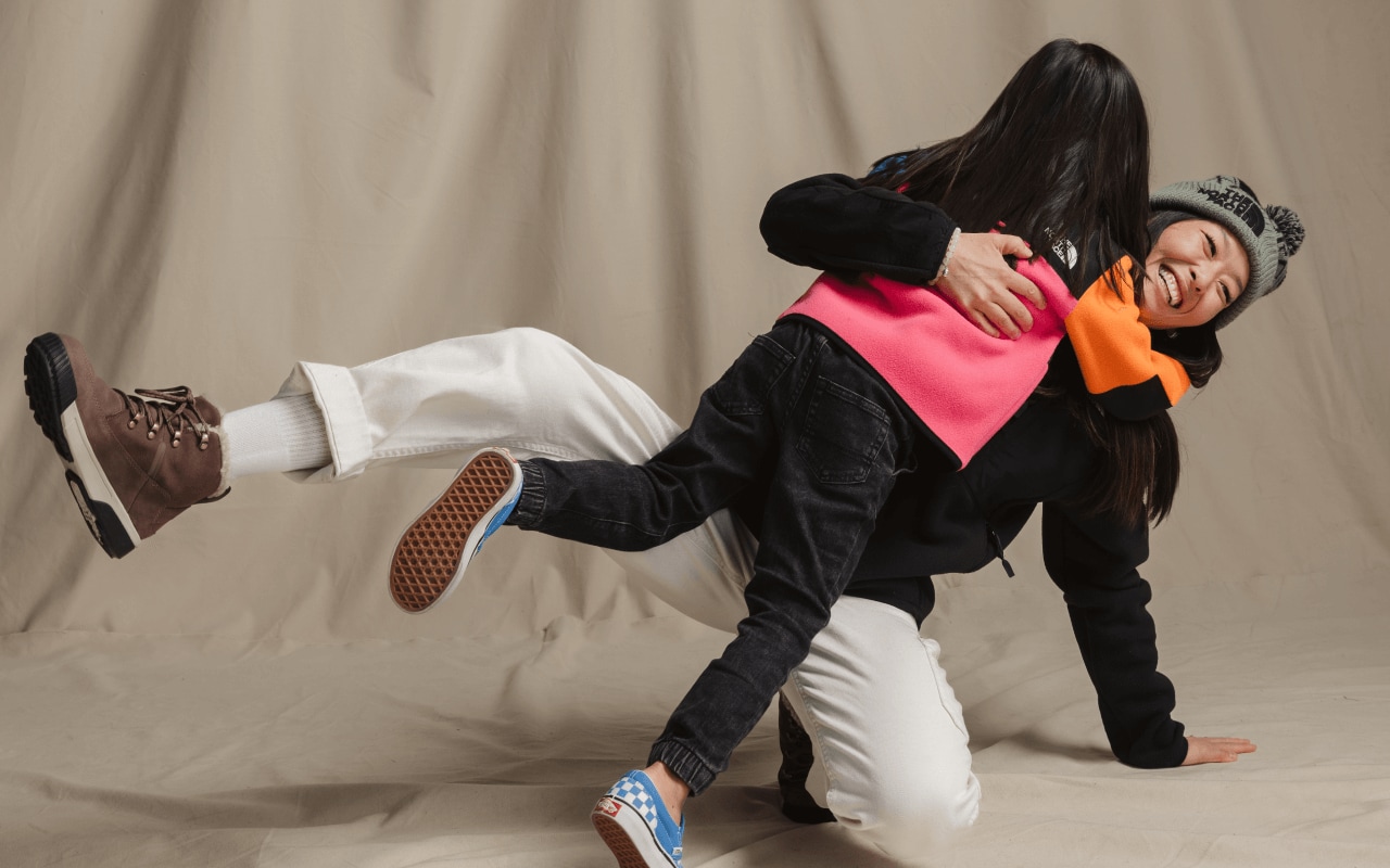 A parent and child hug in front of a beige background while wearing Denali Jackets.  