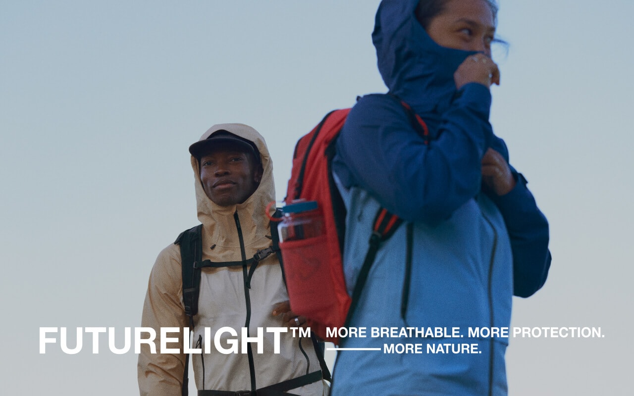 Two Hikers admire the view from the summit while wearing the Frontier FUTURELIGHT™ Jacket.  
