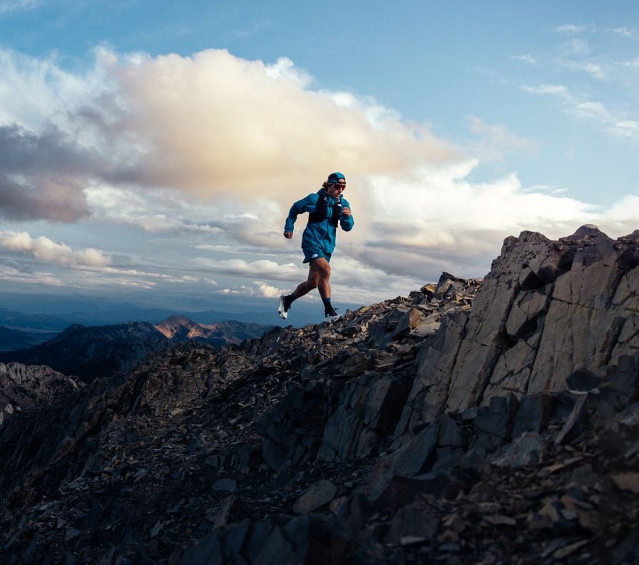 A person is running on the ridge of a mountain in gear from The North Face.  