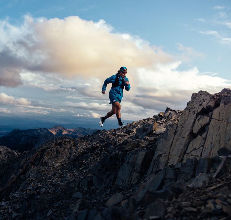 Une personne court sur la crête d’une montagne vêtue en The North Face. 
