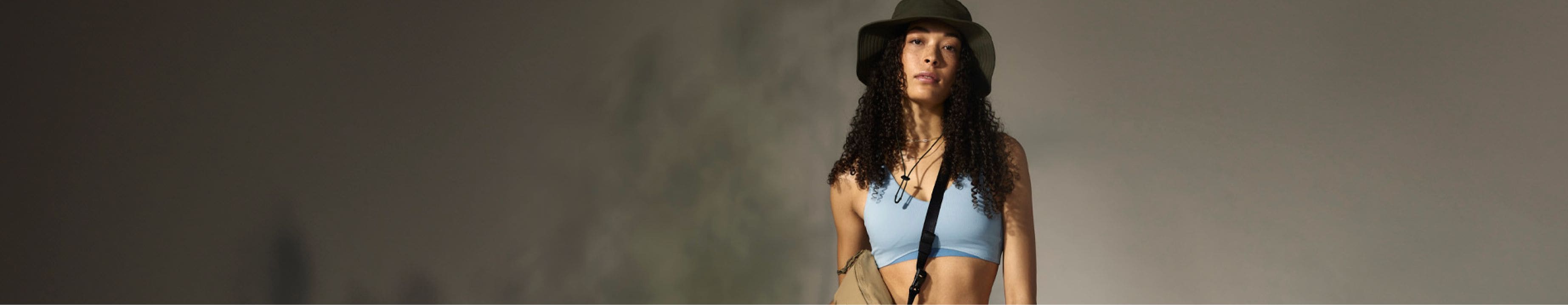 A person is wearing the Horizon Breeze Brimmer Hat and the Dune Sky Valley Shine Bra. Text reads: “Dune Sky: Feel fresh (and focused) with FlashDry™ materials.” 