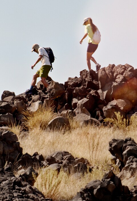 A man and woman hike over a rocky ridge with packs from The North Face.