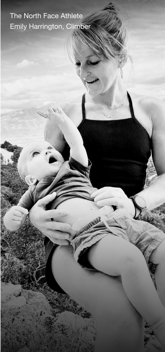 Black and white image of The North Face Athlete Emily Harrington holding her toddler while sitting in an alpine landscape.