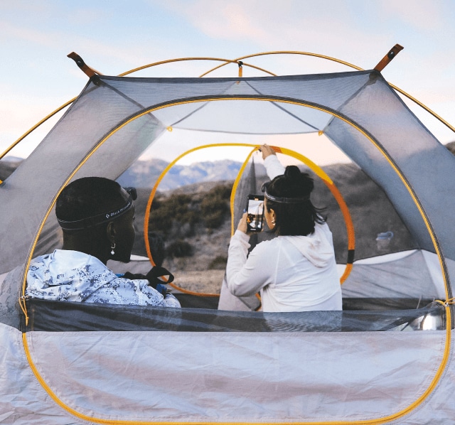 Two people sit in a tent from The North Face with their backs to the camera.