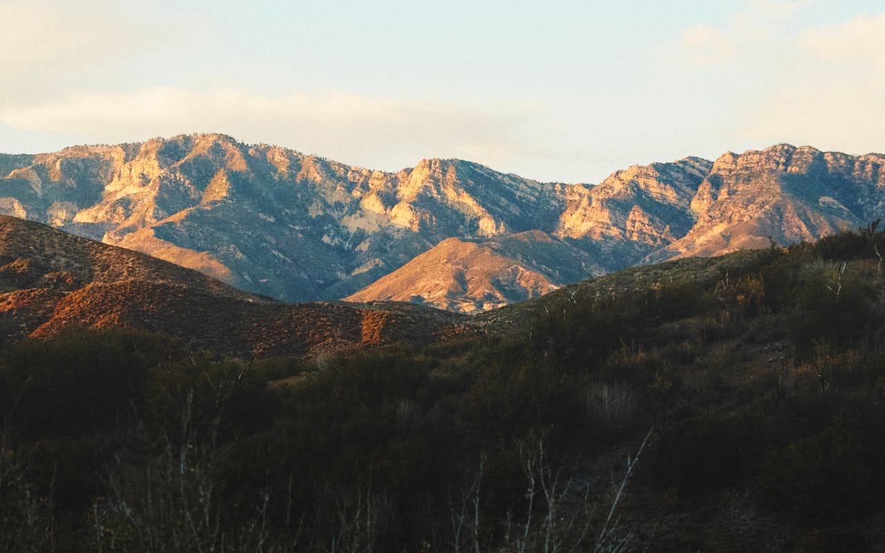 The sun illuminates a mountain range in the distance.