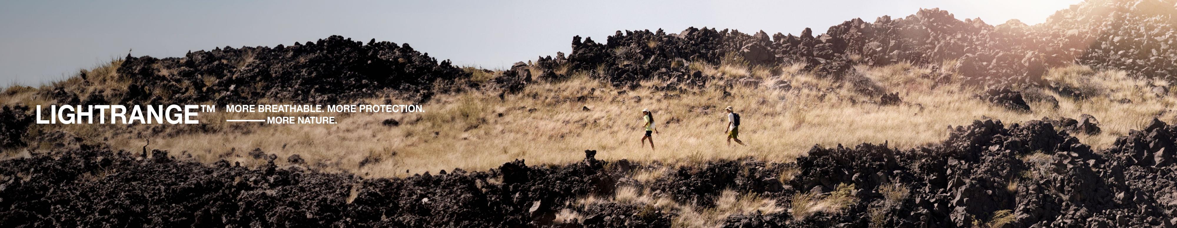 Two distant hikers trek through a desert landscape. 