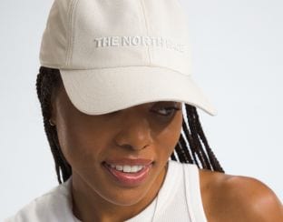 Studio shot of a woman in a white hat from The North Face.
